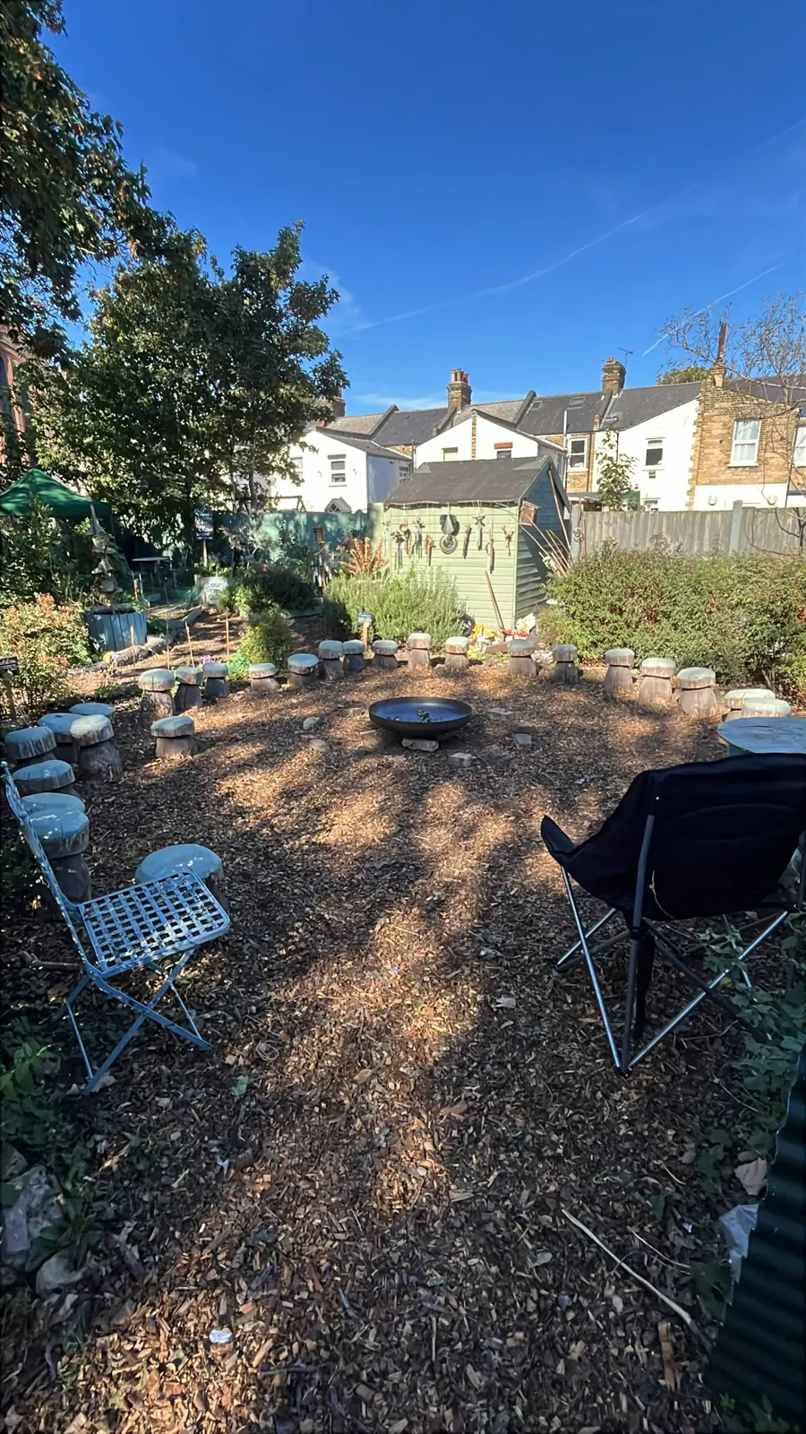 The open circle of woodchip ringed by the mushroom stools, with chairs set out in the sun