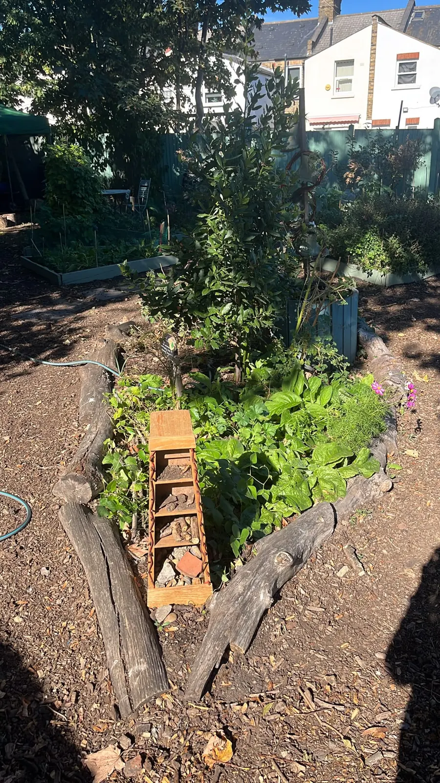 A bed edged with logs, with a small wooden insect tower in the middle